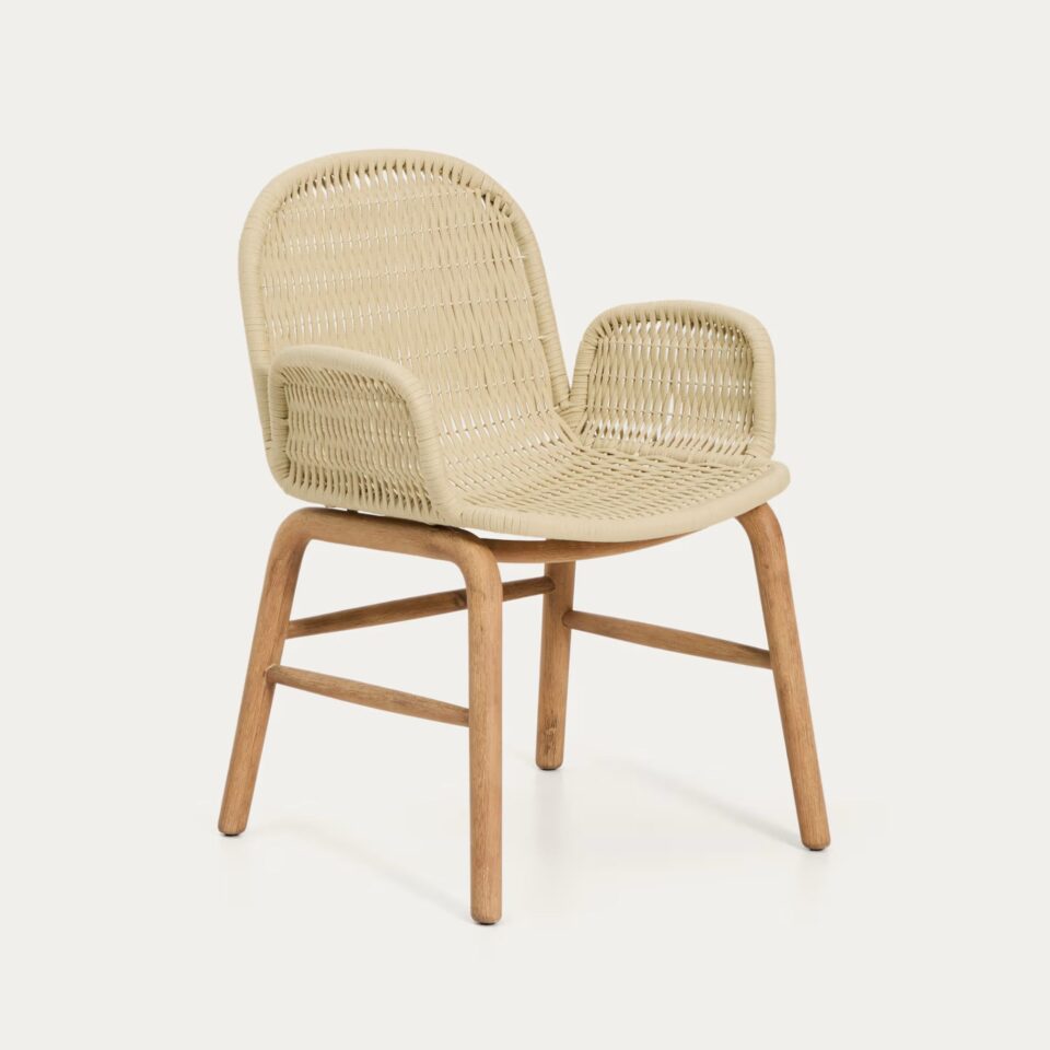 Vrtni stol Alipa v bež barvi, s pletenim sedežem in nasloni za roke ter masivnimi lesenimi nogami, ustvarja naraven videz.