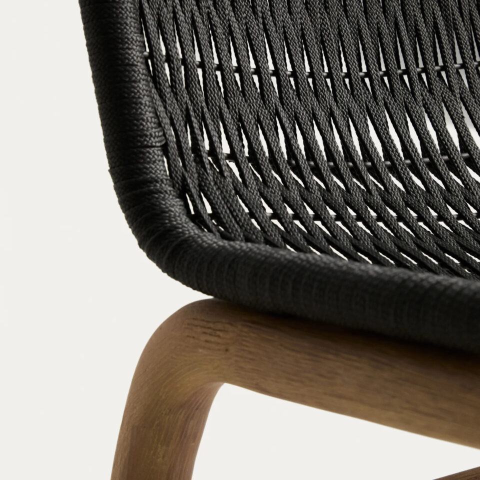 Približni posnetek ukrivljenega naslonjala vrtnega stola Alipa iz črne pletene vrvi in dela akacijevega lesenega okvirja na belem ozadju.