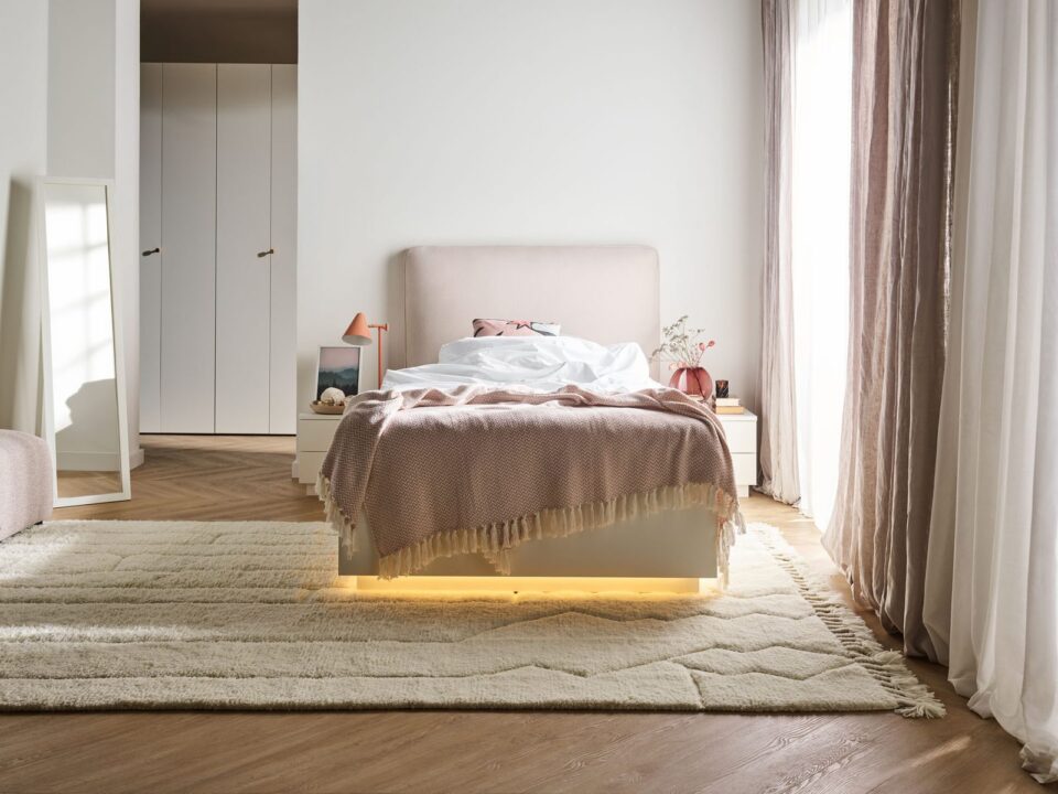Postelja Sova v beli barvi z roza oblazinjenim vzglavjem in LED podnožjem
